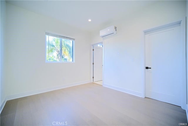 empty room featuring hardwood / wood-style flooring and an AC wall unit