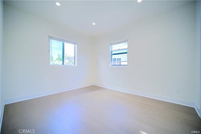 spare room with a healthy amount of sunlight and hardwood / wood-style floors