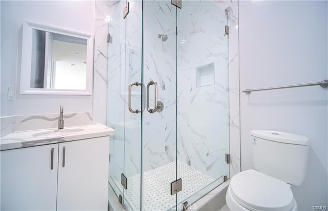 bathroom featuring vanity, a shower with shower door, and toilet