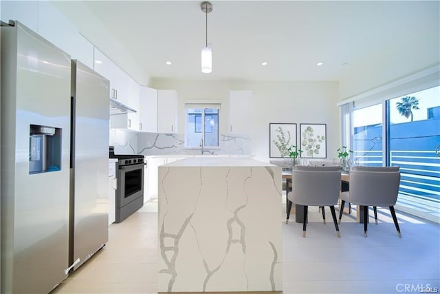 kitchen featuring pendant lighting, white cabinetry, a center island, exhaust hood, and stainless steel appliances