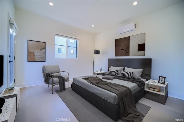 bedroom with a wall unit AC and light hardwood / wood-style floors