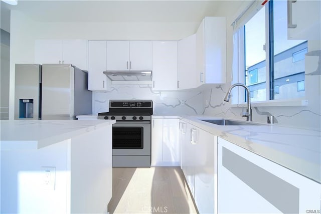 kitchen featuring stainless steel appliances, sink, white cabinets, and light stone counters