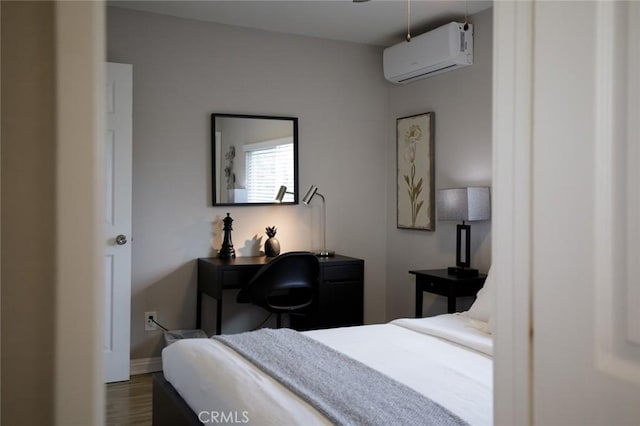 bedroom with a wall unit AC, baseboards, and dark wood-type flooring