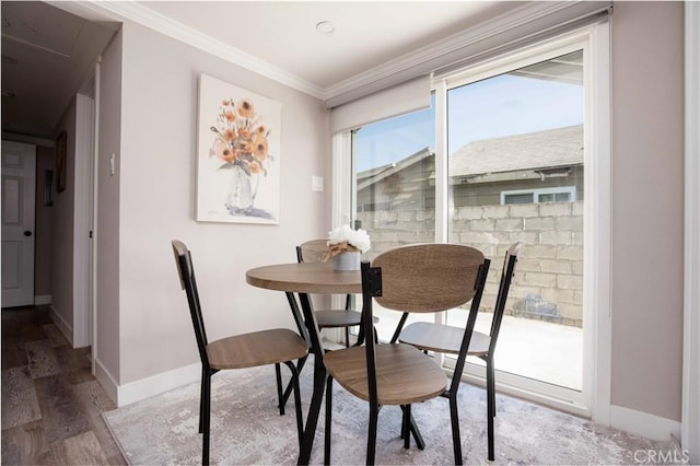 dining space with attic access, baseboards, crown molding, and wood finished floors