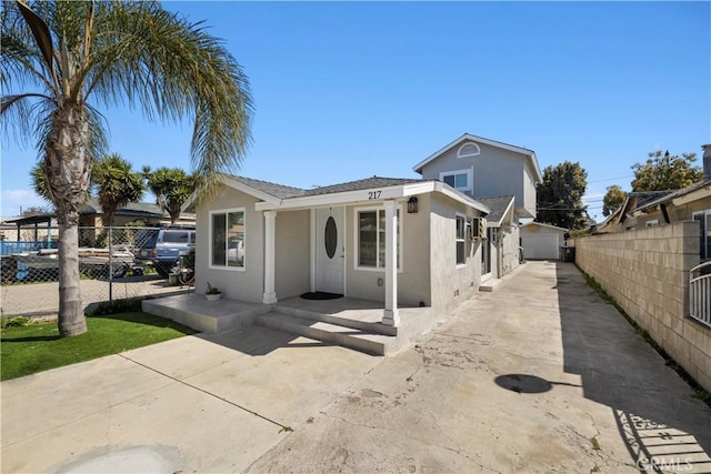 bungalow-style home featuring an outbuilding, a patio area, fence, and stucco siding