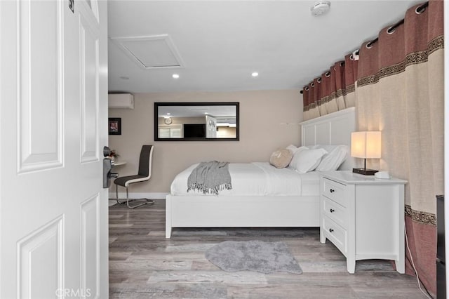 bedroom with a wall mounted air conditioner, wood finished floors, attic access, and recessed lighting