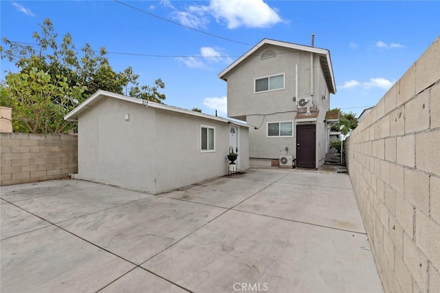 rear view of property featuring stucco siding, a fenced backyard, and a patio