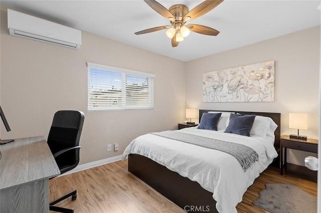 bedroom with a ceiling fan, baseboards, an AC wall unit, and wood finished floors