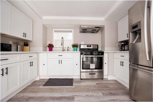 kitchen featuring light countertops, appliances with stainless steel finishes, ornamental molding, white cabinetry, and a sink