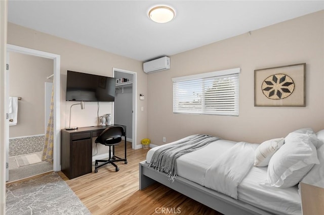 bedroom with baseboards, light wood-style floors, a spacious closet, a wall mounted AC, and a closet