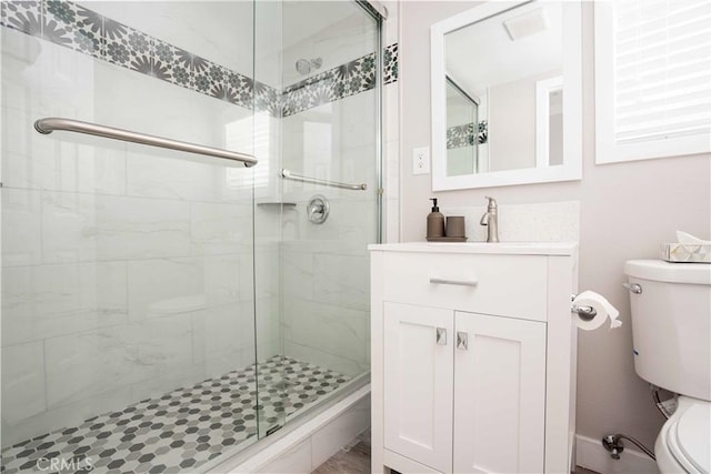 bathroom with vanity, a shower stall, and toilet