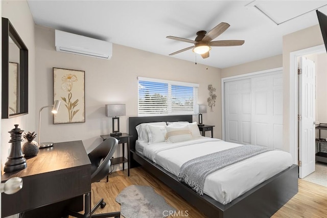 bedroom with a closet, ceiling fan, light wood finished floors, and a wall mounted AC