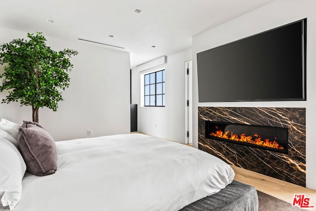 bedroom featuring a premium fireplace and hardwood / wood-style floors