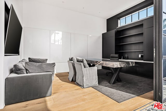 home office with built in shelves, wood-type flooring, and a high ceiling