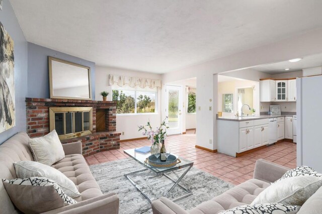 living room with light tile patterned flooring, a brick fireplace, and baseboards