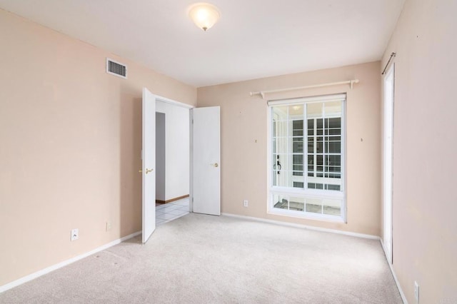 carpeted spare room featuring baseboards and visible vents