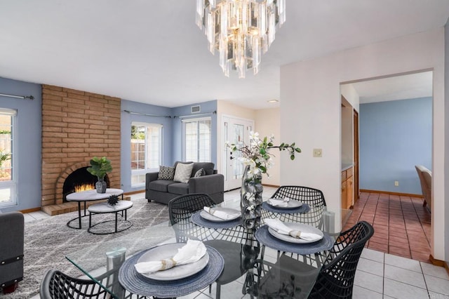 dining room featuring visible vents, an inviting chandelier, a fireplace, light tile patterned floors, and baseboards