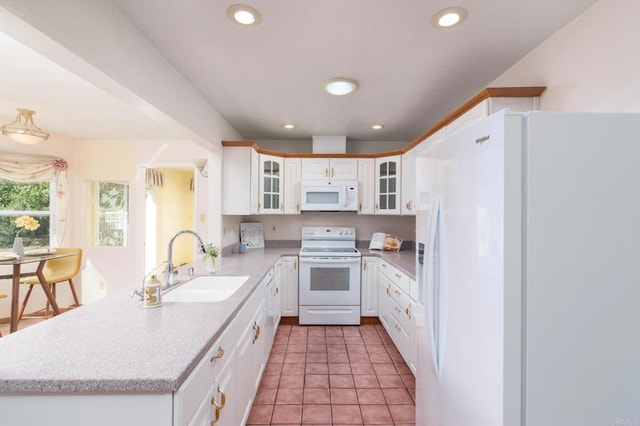 kitchen featuring white appliances, a peninsula, recessed lighting, a sink, and light countertops