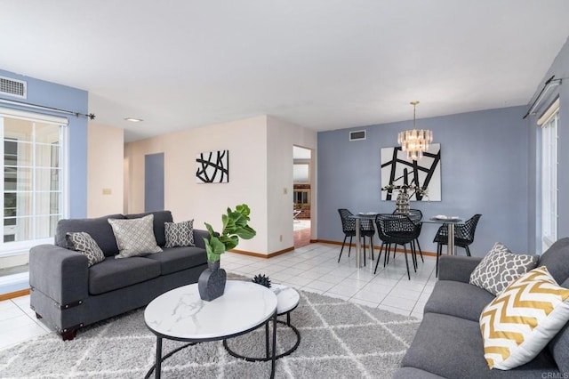 living area with tile patterned flooring, visible vents, baseboards, and a notable chandelier