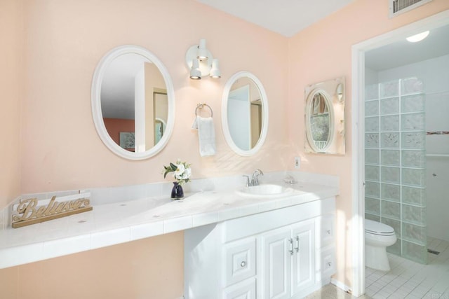 bathroom with tile patterned floors, visible vents, toilet, a tile shower, and vanity