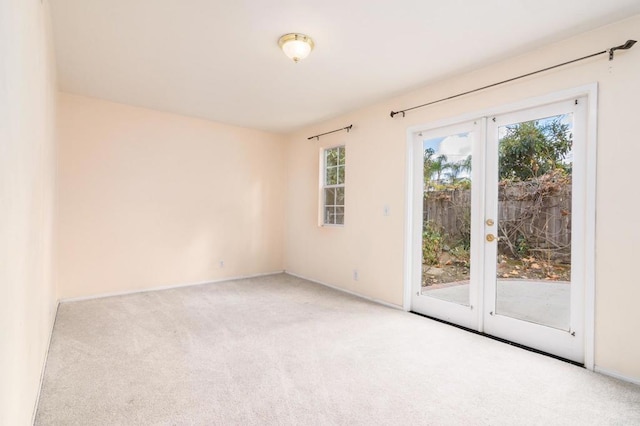 carpeted spare room featuring french doors and baseboards