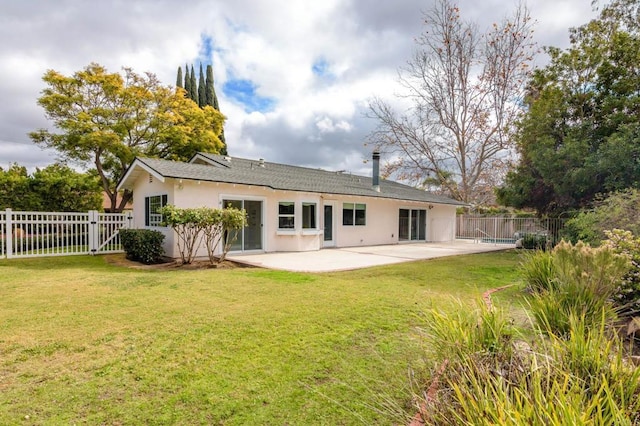 rear view of property featuring a gate, stucco siding, a lawn, and a patio area