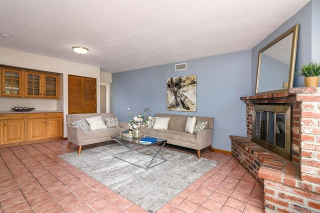 living area with light tile patterned floors, visible vents, and a fireplace