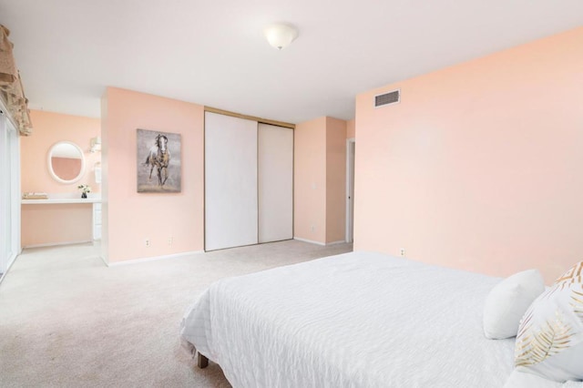 carpeted bedroom with baseboards, visible vents, a closet, and connected bathroom