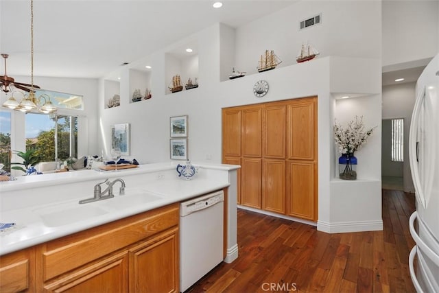 kitchen featuring light countertops, visible vents, a high ceiling, a sink, and white appliances