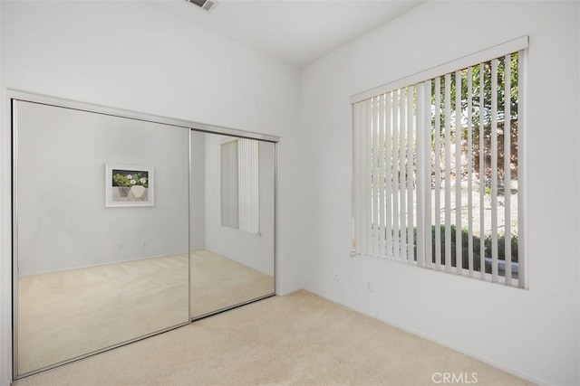 unfurnished bedroom featuring light carpet and a closet