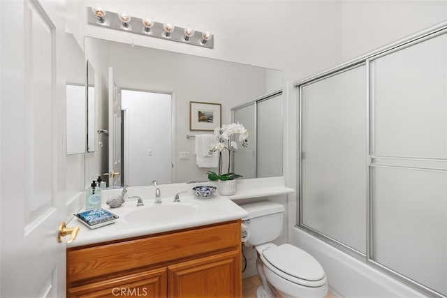 bathroom featuring enclosed tub / shower combo, toilet, and vanity