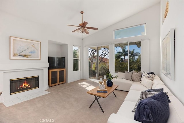 living room with light carpet, high vaulted ceiling, a fireplace with flush hearth, and a ceiling fan