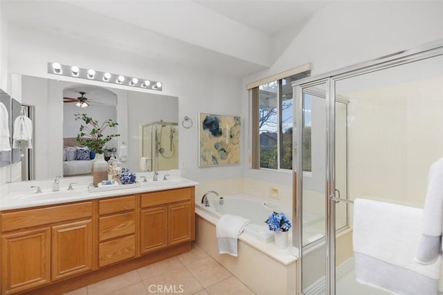 ensuite bathroom with tile patterned flooring, a sink, a shower stall, and a bath