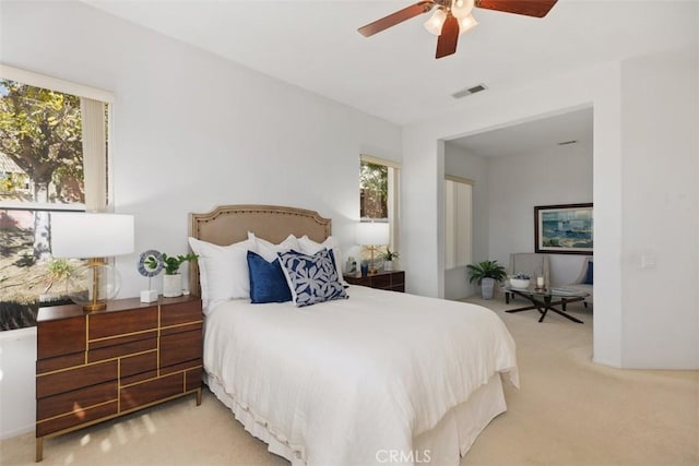 bedroom with light carpet, visible vents, and a ceiling fan