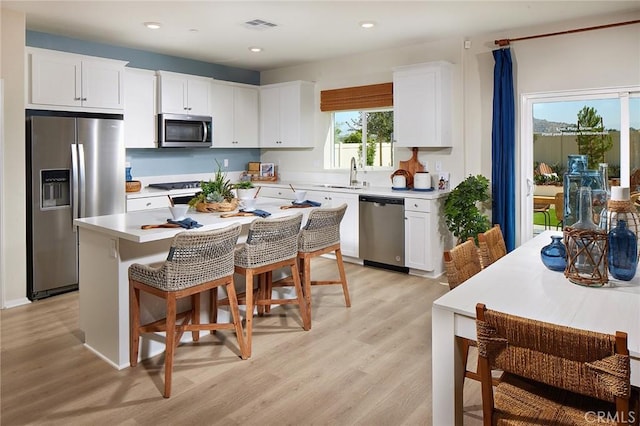 kitchen with sink, a breakfast bar area, appliances with stainless steel finishes, a kitchen island, and white cabinets