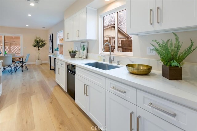 kitchen featuring sink, a wealth of natural light, white cabinets, and light hardwood / wood-style flooring