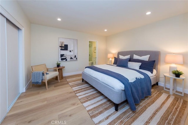 bedroom with ensuite bathroom and light hardwood / wood-style floors