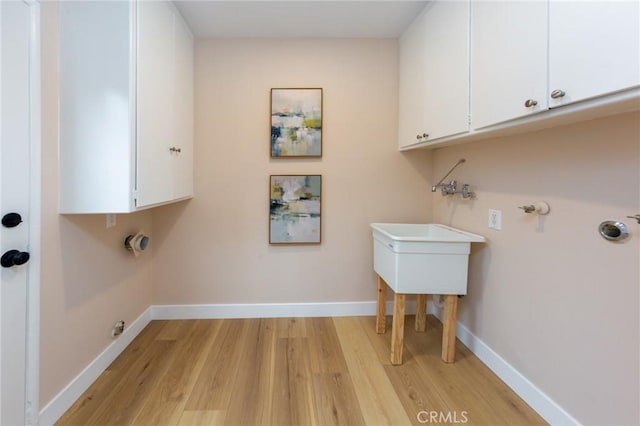 clothes washing area with cabinets, gas dryer hookup, and light hardwood / wood-style floors