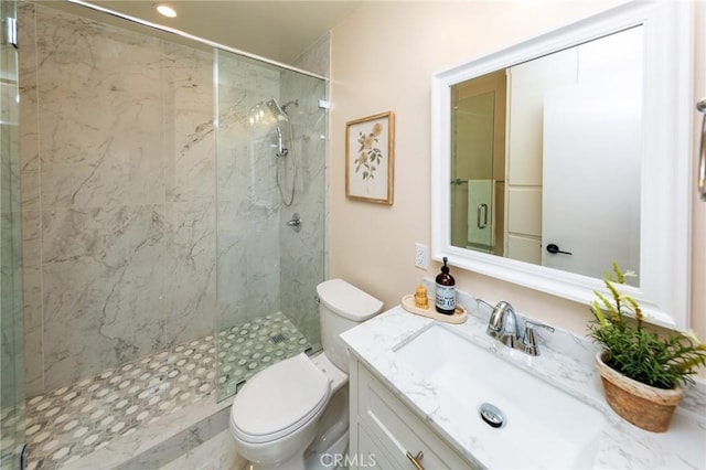 bathroom featuring vanity, a shower with shower door, and toilet