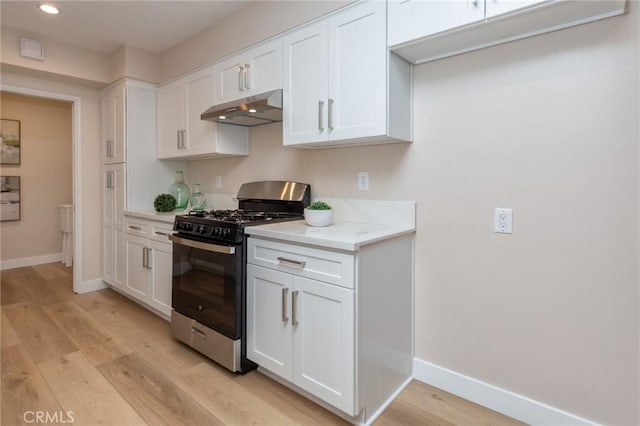 kitchen with light stone countertops, white cabinets, light hardwood / wood-style floors, and stainless steel gas stove