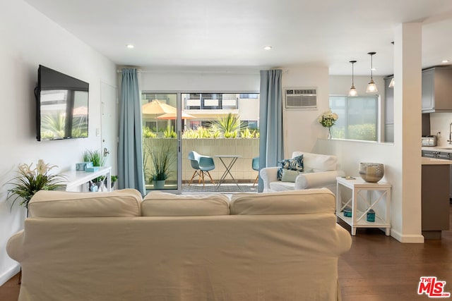 living room with plenty of natural light, dark hardwood / wood-style floors, and an AC wall unit