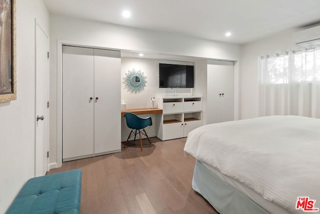 bedroom with a wall unit AC and light hardwood / wood-style floors