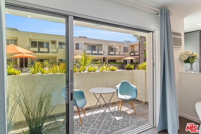 doorway to outside featuring hardwood / wood-style flooring, a wealth of natural light, and a wall unit AC