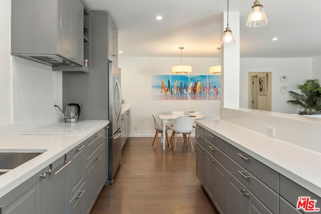 kitchen featuring pendant lighting, dark hardwood / wood-style floors, gray cabinets, and stainless steel refrigerator