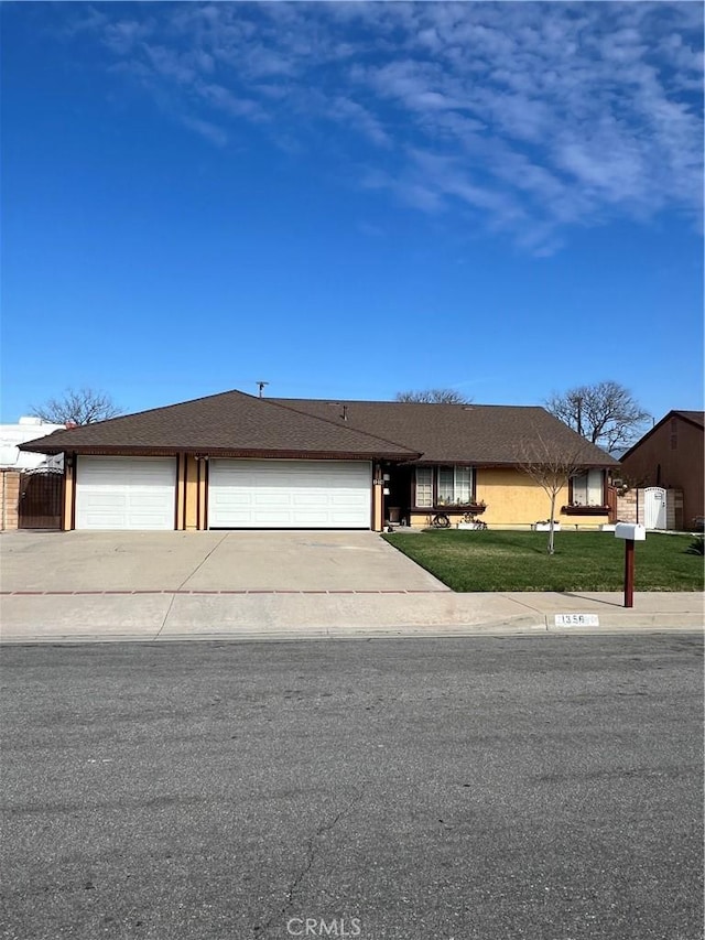 view of front of house with a front yard, concrete driveway, roof with shingles, and an attached garage