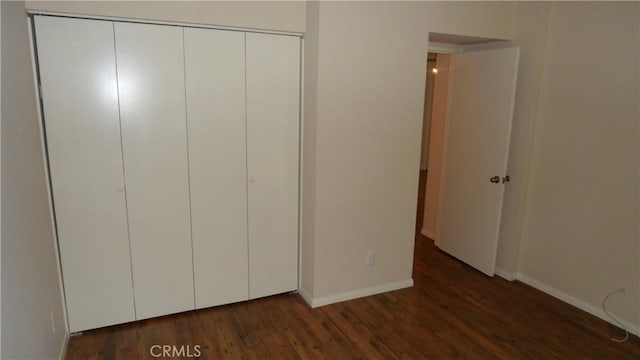 unfurnished bedroom featuring dark wood-type flooring and a closet