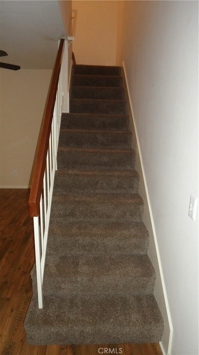 stairs with hardwood / wood-style floors and ceiling fan