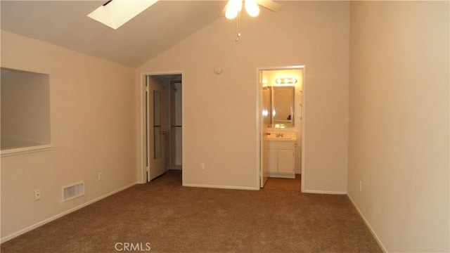 unfurnished bedroom featuring sink, ensuite bath, lofted ceiling with skylight, and carpet