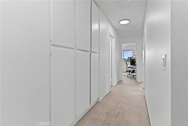 corridor with light carpet and a textured ceiling