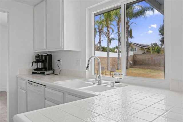 kitchen featuring white cabinetry, dishwasher, sink, and tile counters